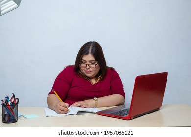 Obese woman typing her new diet from an online page on laptop from home office. fat model