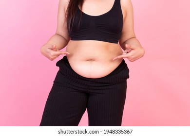 Obese women pointing at her belly. Happy Overweight woman standing in pink background. Obese fat woman, plus size fashion model, fat woman on pink background. 