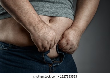 Obesity Concept, Close Up Of Overweight Man Trying To Wear Too Small Jeans