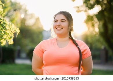 Obesity People. Plus Size Woman. Body Positive. Weight Confidence. Joyful Chubby Young Obese Overweight Girl Smiling Outdoors In Defocused Green Park Street Landscape.