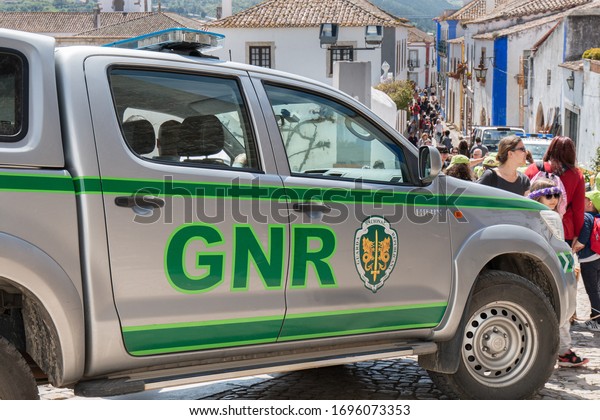 Obidos, Portugal - April 12, 2019:\
car of the Republican National Guard (GNR) parked in the middle of\
a pedestrian street where tourists pass on a spring\
day