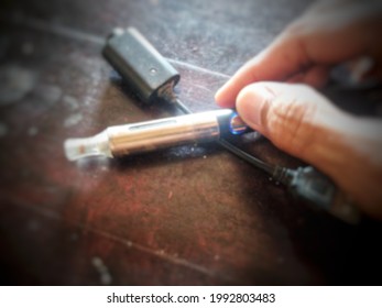 Object Defocused Of Vape Pen And Men Hand On The Wood Table Blur Lens Defocused