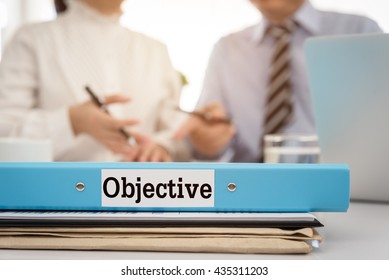 Objective document folder with staff and manager in meeting room.