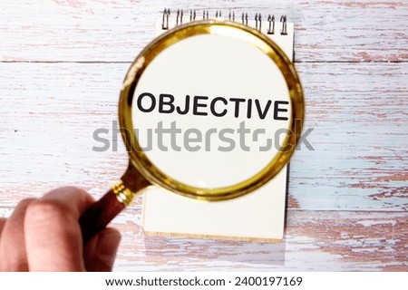 OBJECTIVE text seen through magnifying glasses on a notepad