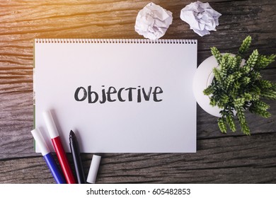 Objective Word With Notepad And Green Plant On Wooden Background