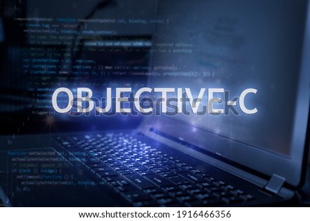 Objective-C inscription against laptop and code background. Learn programming language, computer courses, training. 