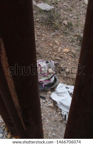 objects abandoned by border crossers visible when looking south into Mexico through pedestrian style fencing along the US Mexico border in Tucson Sector Arizona 4478