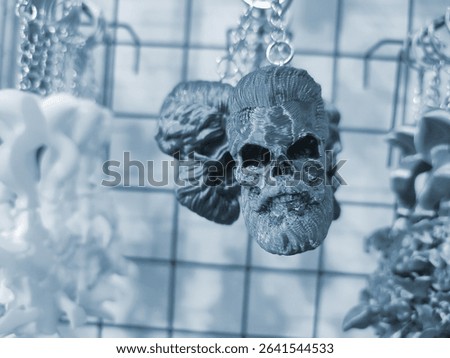 Objects keychains in form of skull of man, models of toys printed on 3D printer from molten plastic hanging on chain. Concept 3D Printing. New modern 3D Printing additive technology. Blue color