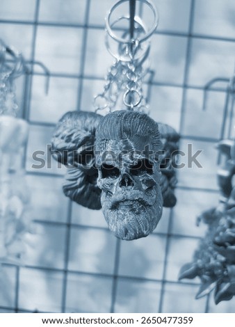 Objects keychains in form of skull of man, models of toys printed on 3D printer from molten plastic hanging on chain. Concept 3D Printing. New modern 3D Printing additive technology. Blue color