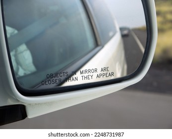Objects in mirror are closer than they appear inscription on the car rear view mirror closeup, a driver warning and safety concept, Car's Reflection In Rear View blurred background