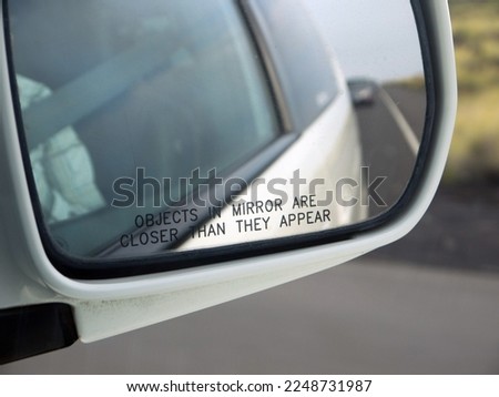Objects in mirror are closer than they appear inscription on the car rear view mirror closeup, a driver warning and safety concept, Car's Reflection In Rear View blurred background