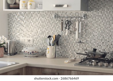 Objects on kitchen workspace with mosaic tile wall. Traditional apartment interior, Italy. Ceramic tableware and kitchenware.