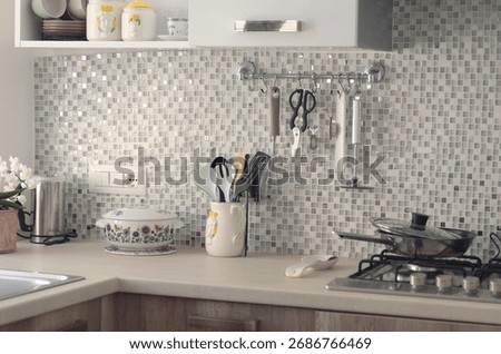 Objects on kitchen workspace with mosaic tile wall. Traditional apartment interior, Italy. Ceramic tableware and kitchenware.