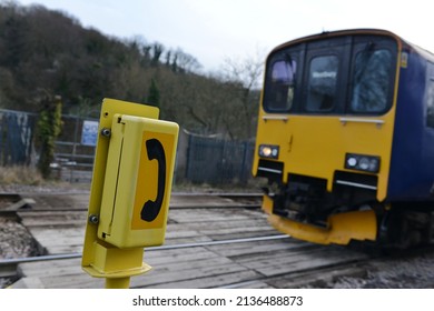 Oblique angle view of a generic emergency phone by a railway level crossing as a train approaches - image has a shallow depth of field with focus on the phone - Powered by Shutterstock