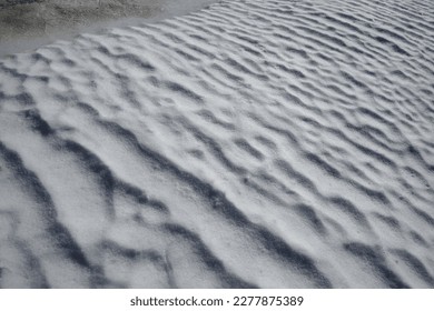An oblique shot or diagonal of a snow field with waves formed by the wind on a March morning - Shutterstock ID 2277875389