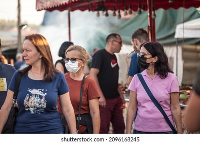OBRENOVAC, SERBIA - MARCH 20, 2021: Two women, friends, wearing a face mask in front of a crowd in the streets of Obrenovac on Obrenovacki vasar on coronavirus covid 19 crisis.