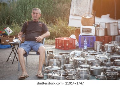 OBRENOVAC, SERBIA - SEPTEMBER 26, 2021: Selective blur on a man, a merchant, selling second hand kitchenware: metalware like pots and saucepans in the flea market of Obrenovacki Vasar. 