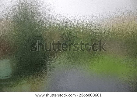Obscure glass in a bathroom, also known as privacy glass, blurred garden in background