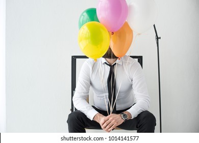 Obscured View Of Businessman With Colorful Balloons Sitting On Chair