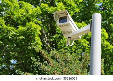 Observation camera on a column against green branches