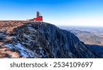 Observation tower on the edge of the cliffs and rocky steep summit with remnants of snow in Snezne jamy place in Krkonose mountains with scenic view to the landscape during autumn beautiful day.