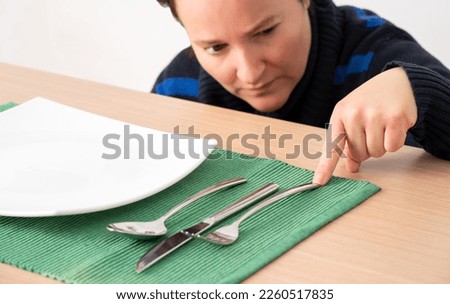 Obsessive compulsive woman lining up eating cutlery on a table