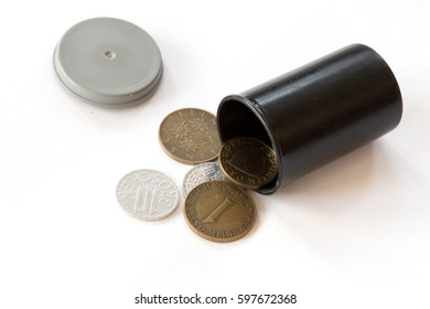 Obsolete Austrian Schillings Spilling Out Of A Plastic Film Canister On White