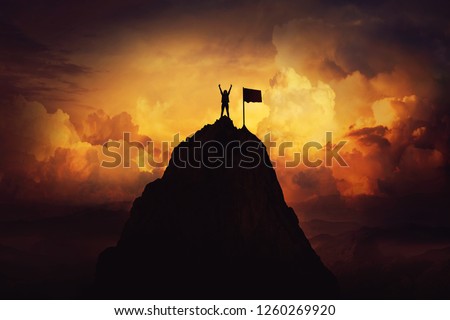 Obstacle overcome as a woman raise hands up on the top of a mountain reaching the finish flag. Celebrate victory and success over sunset background. Goal achievement symbol.