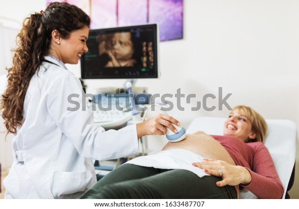 Obstetrician\
examining pregnant belly by ultrasonic\
scan.