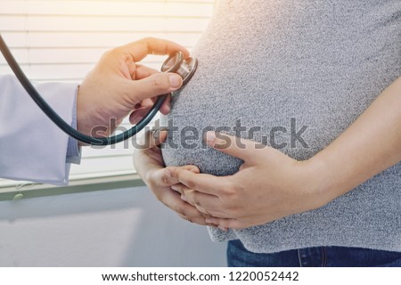 Obstetrician using stethoscope listening to heart rate of fetus, Doctor listen the abdomen of a pregnant woman for check fetal heart sound by stethoscope, Health care pregnant woman.