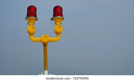 Obstruction Light On The Building With Red Light Bulb And Yellow Pipe The Backdrop Is Sky.