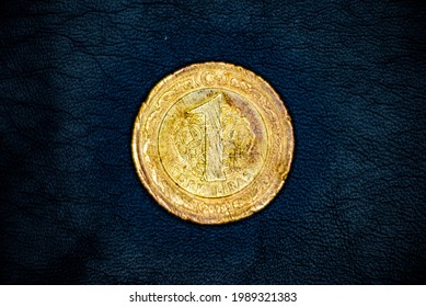Obverse of used, old and damaged Turkish 1(one) lira coin, minted in 2009, on black leather background. Rumi motif.