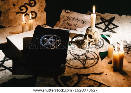 Occult grimoire, black magic book laying on table with occult symbols, candles, pentagrams, fortune telling, ritual, altar, spiritism, secret knowledge, scull 