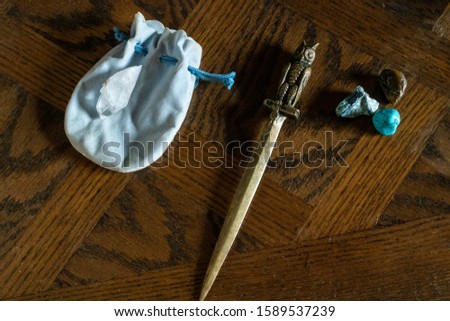 Occult objects on a wooden table. Crystals, dagger and other charms