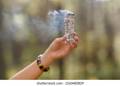 Occult Science And Supernatural Concept - Close Up Of Hand With Smoking White Sage Performing Magic Ritual In Forest