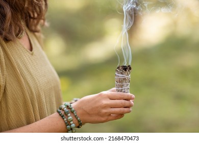 occult science and supernatural concept - close up of woman or witch with smoking white sage performing magic ritual in forest - Shutterstock ID 2168470473