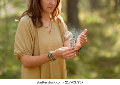 Occult Science And Supernatural Concept - Close Up Of Woman Or Witch With Smoking White Sage Performing Magic Ritual In Forest