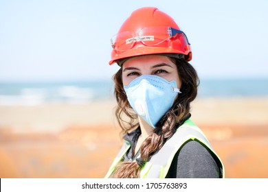 Occupational health and safety (OHS) woman staff (engineer) looking at the camera with protective mask for coronavirus (covid-19) in the construction field.