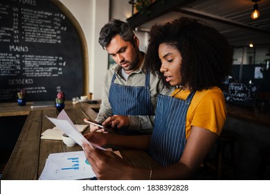 Occupied business co-workers sorting out bank statements for the week working at trendy coffee shop - Powered by Shutterstock