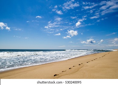 Ocean Beach With Footprints On Sand On Background Of Blue Sky