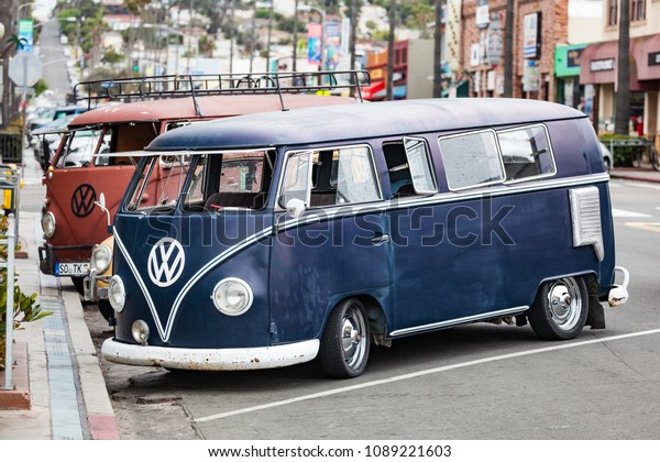 OCEAN BEACH, SAN DIEGO, CALIFORNIA / USA - MAY\
01, 2018: Two old and partially restored or modified Volkswagen\
buses sit parked in the street along Ocean Beach, San Diego,\
California town center.
