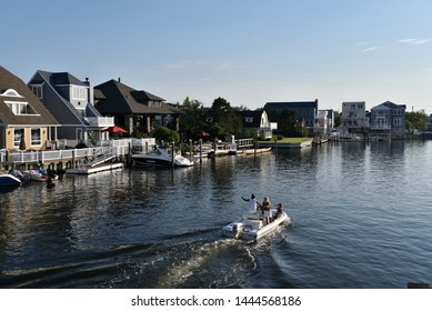 OCEAN CITY, NEW JERSEY/USA - JUNE 27, 2019: A Power Boat Cruises Past Luxury Homes In A Harbor In Margate NJ