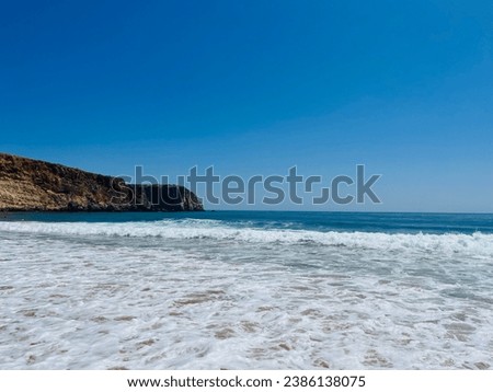 Ocean coastline, rocky coast, sandy beach, foam at the ocean shore