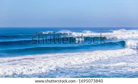 Ocean sea waves rolling towards beach crashing braking along shallow reefs and sandbar a scenic coastline panoramic landscape.
