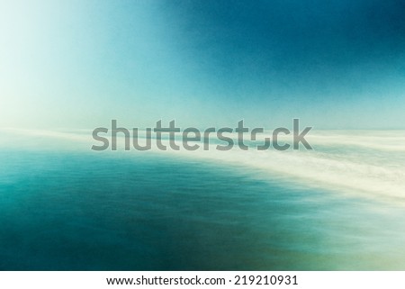An ocean seascape with blurred panning motion.  Image displays abstract, split-toned colors and a pleasing paper grain and texture.