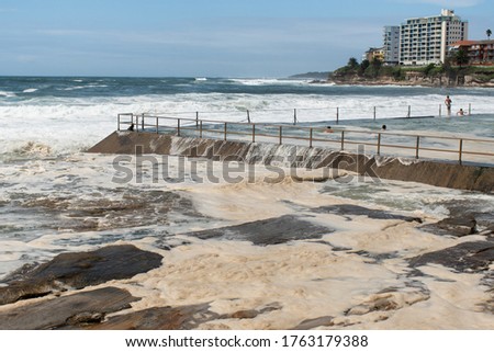 Ocean storm aftermath: A mass of thick foam covered the rocks near rock pool following extreme storm weather at Cronulla, NSW, Australia.