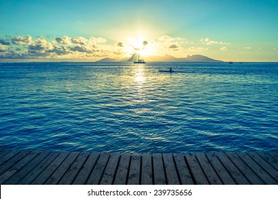 Ocean sunset from a wooden dock with kayak, sailboat, and mountain - Powered by Shutterstock