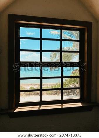 Ocean view behind the window with beach and palm trees