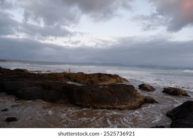 Ocean View at Sunrise with Moon, Rocks and Surfer in the distance on the Beach, Byron Bay Australia - Powered by Shutterstock