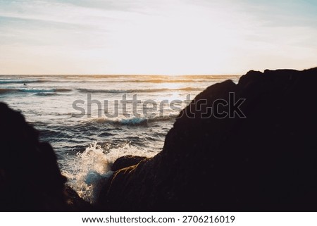 Ocean wave crashes between rocks under the golden sunset, symbolizing energy and transformation. The dynamic motion contrasts with the warm, serene light, representing balance between power and peace